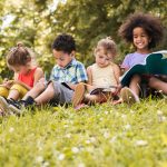 Group of cute kids writing in notebooks at the park.